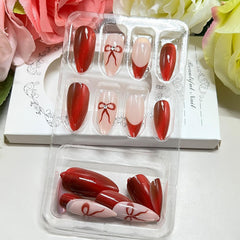 Uñas postizas con lazo rojo para un look elegante.