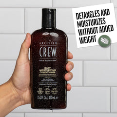 Manos aplicando el acondicionador American Crew distribuyen la crema de forma uniforme.