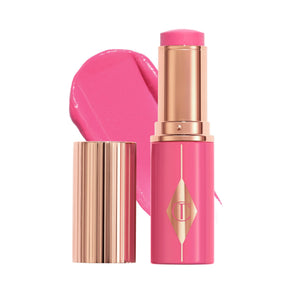 Charlotte Tilbury Unreal Blush Stick aplicado suavemente en la mejilla para brillo jugoso.