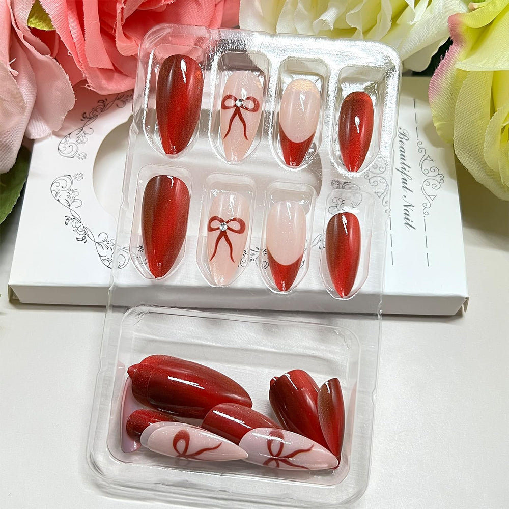 Uñas postizas con lazo rojo para un look elegante.